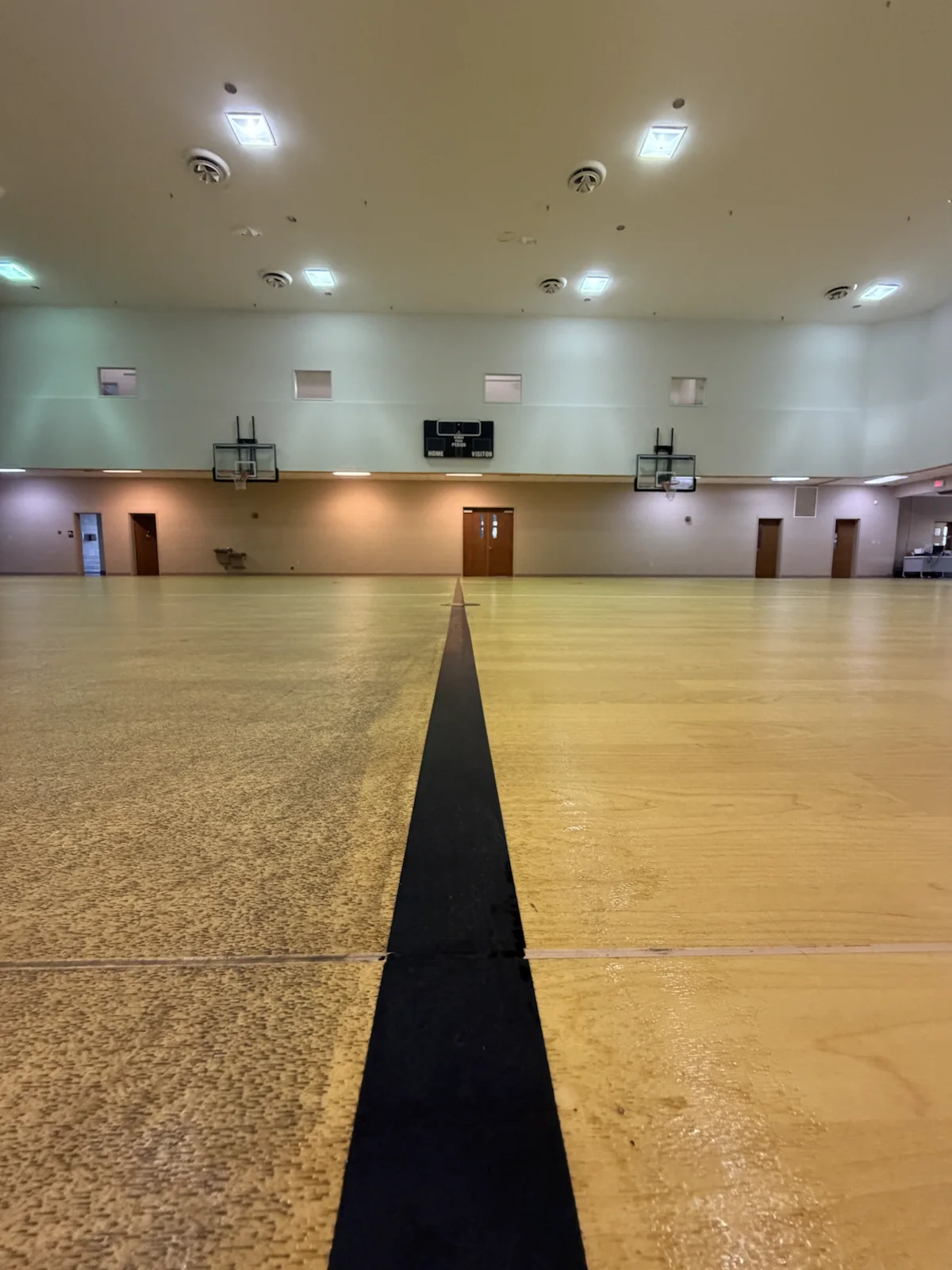 Basketball court during deep cleaning with treated and untreated floor sections visible