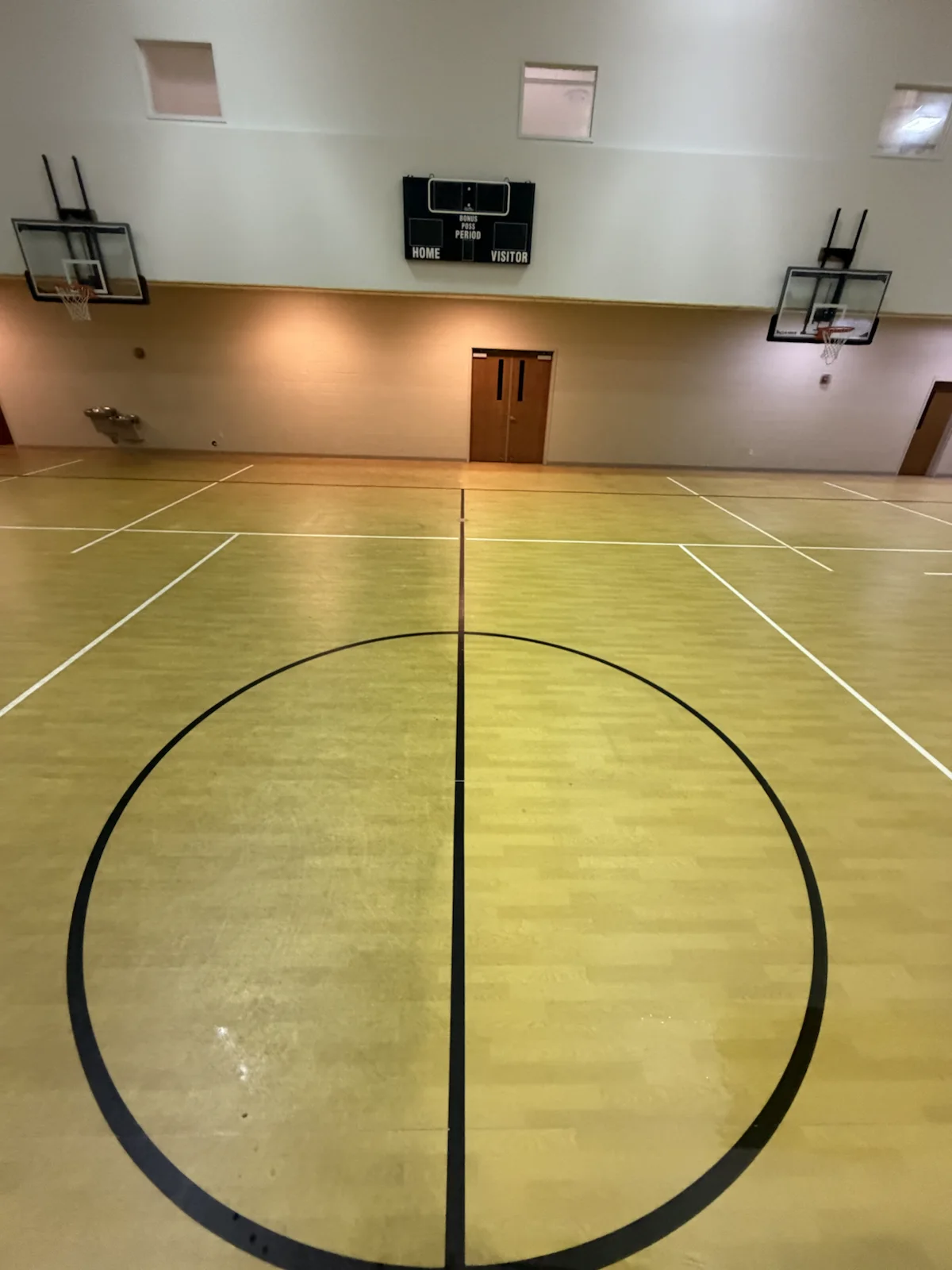Wide view of a hardwood court during professional surface cleaning