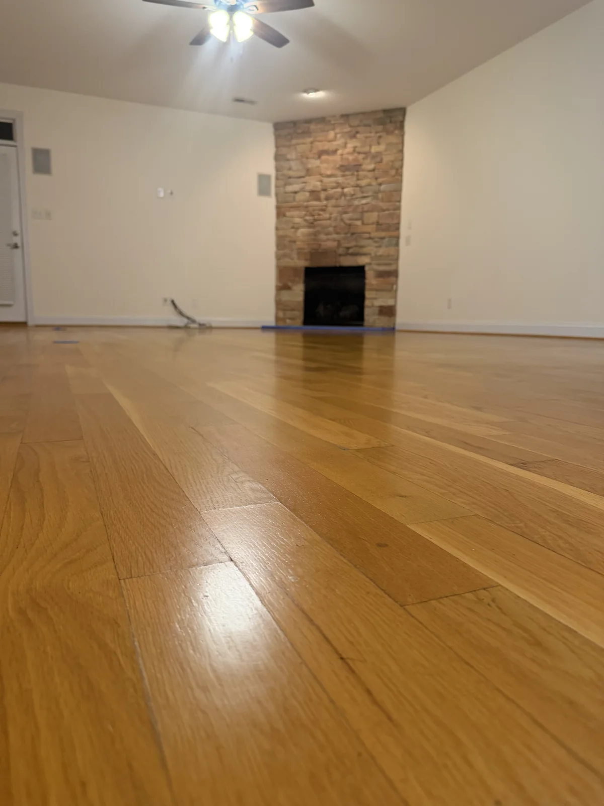 Oak floor leading to a stone fireplace after Mop & Glo removal and a new polyurethane coat