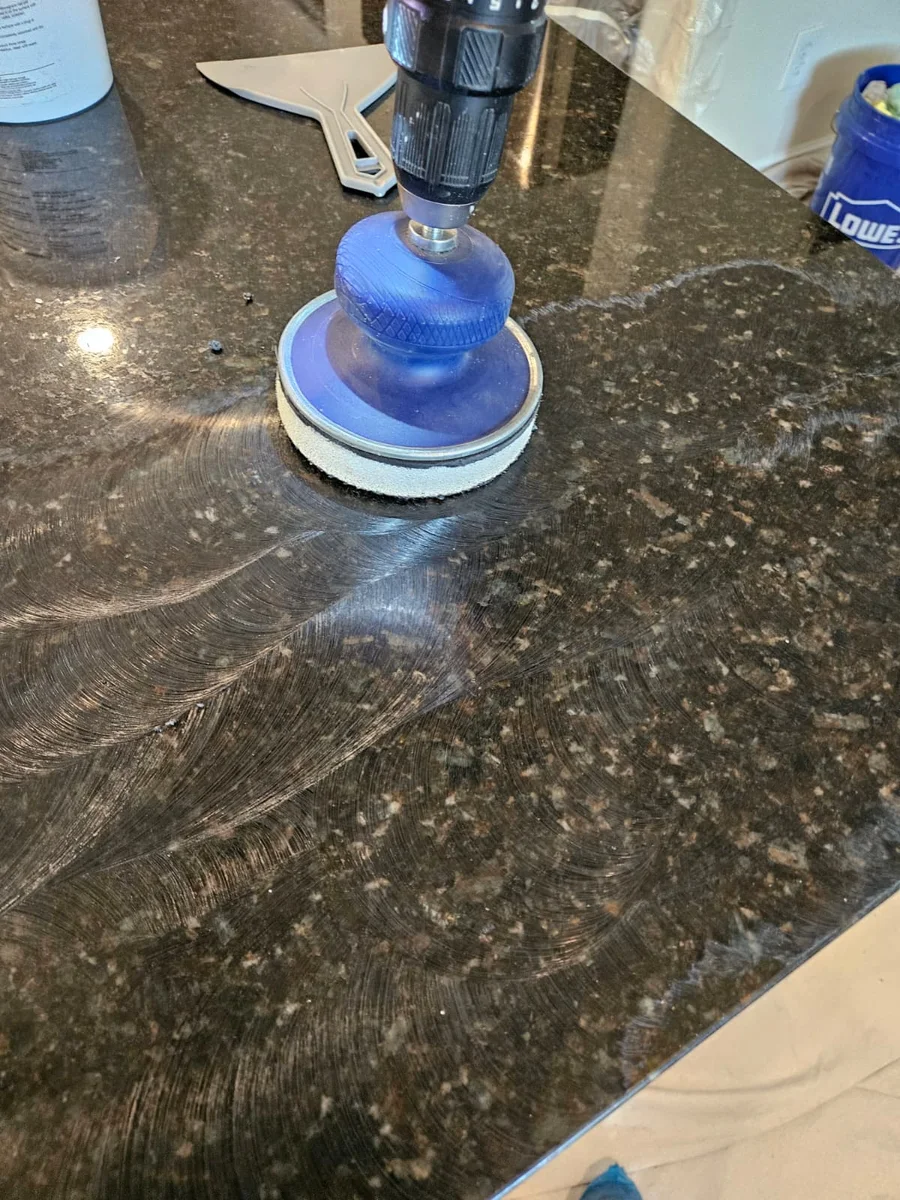 Diamond polishing pad working across a dark granite countertop