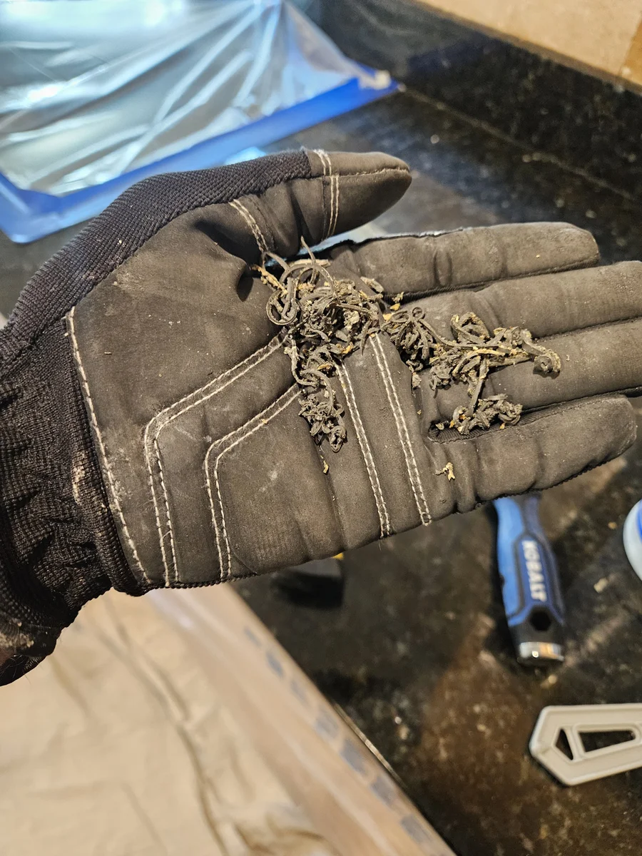 Failed old sealant removed from a dark granite countertop