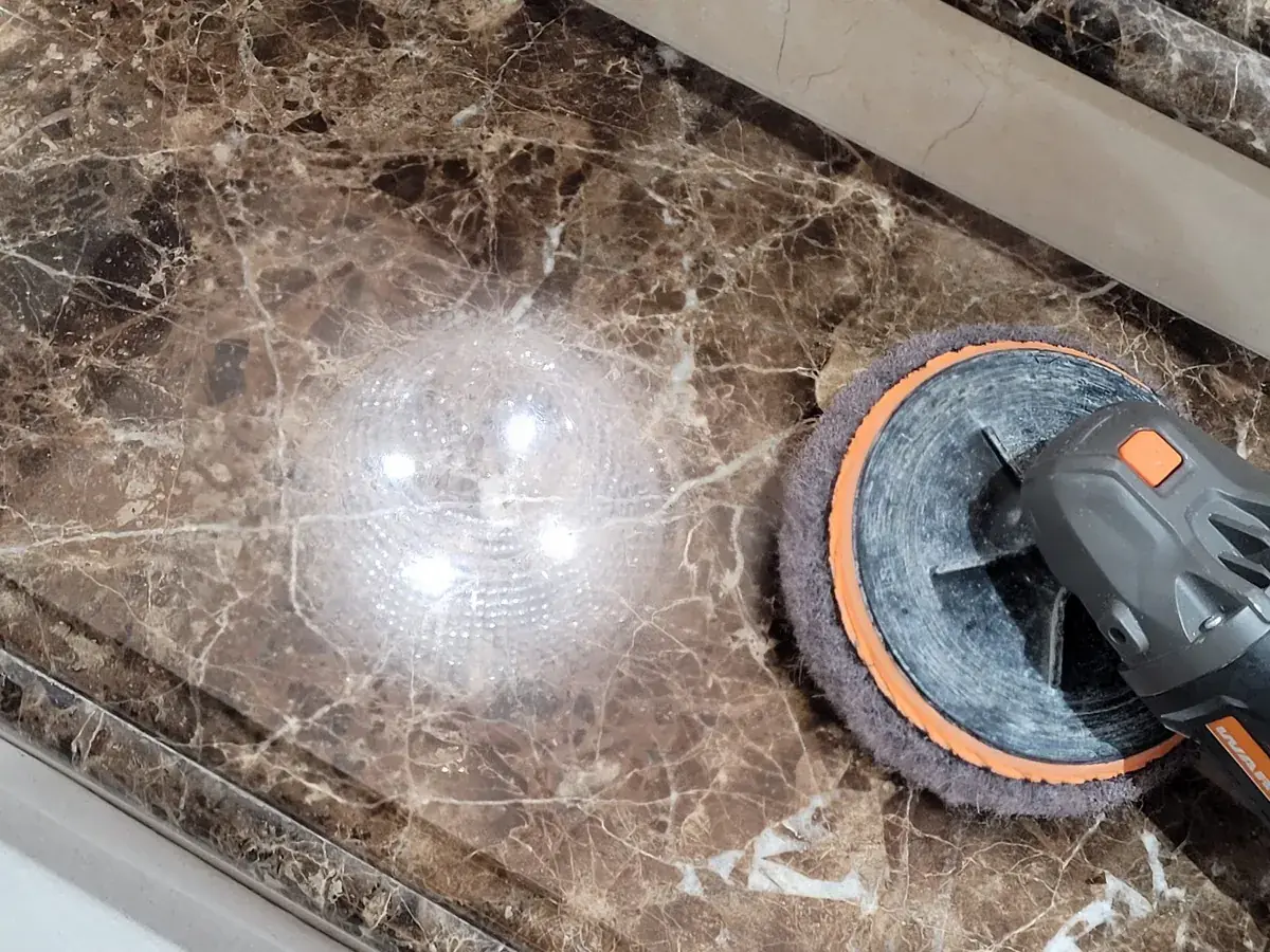 Professional polishing equipment refining the surface of dark Emperador marble