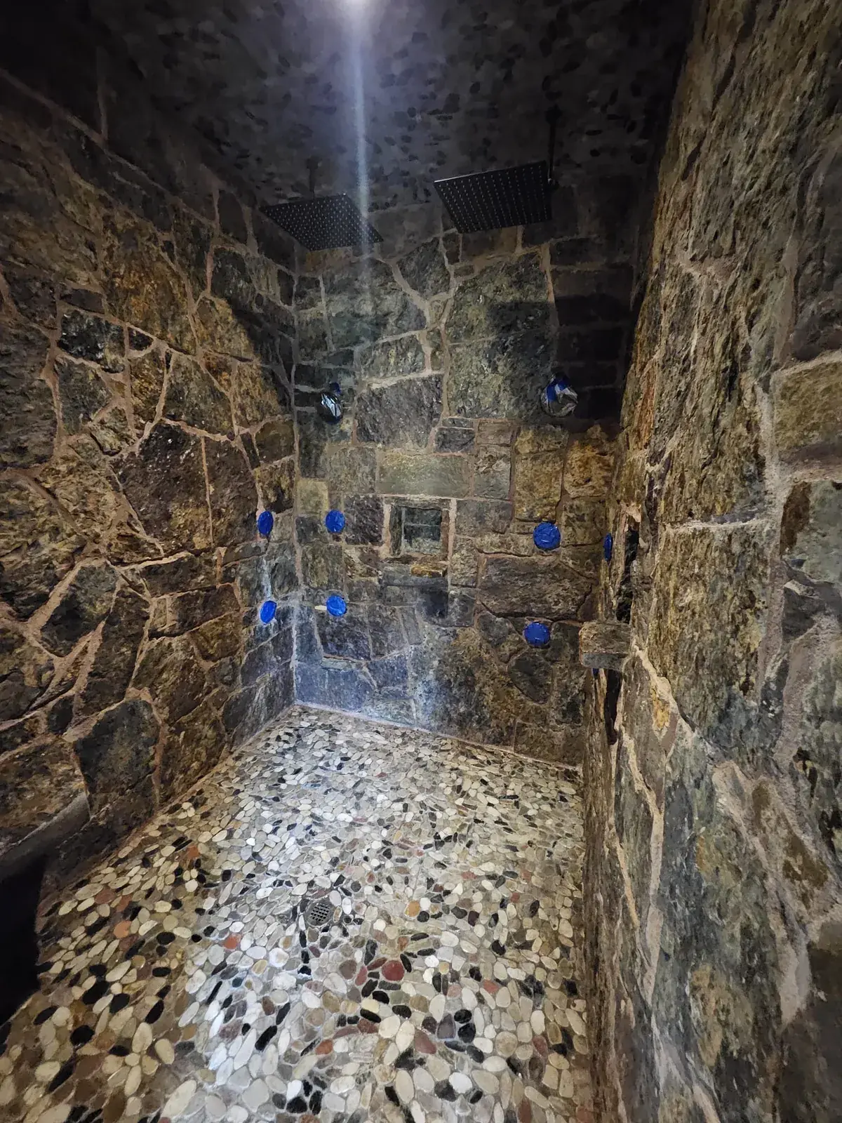 Natural-stone shower inspected around water-exposed joints and surfaces