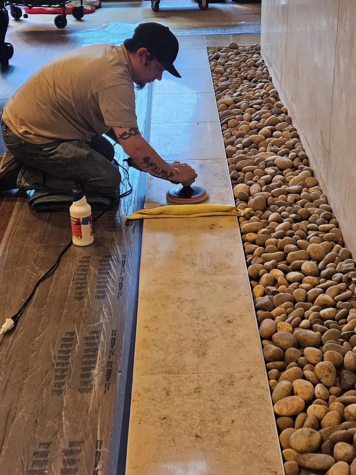 Technician polishing a travertine floor with surrounding surfaces protected