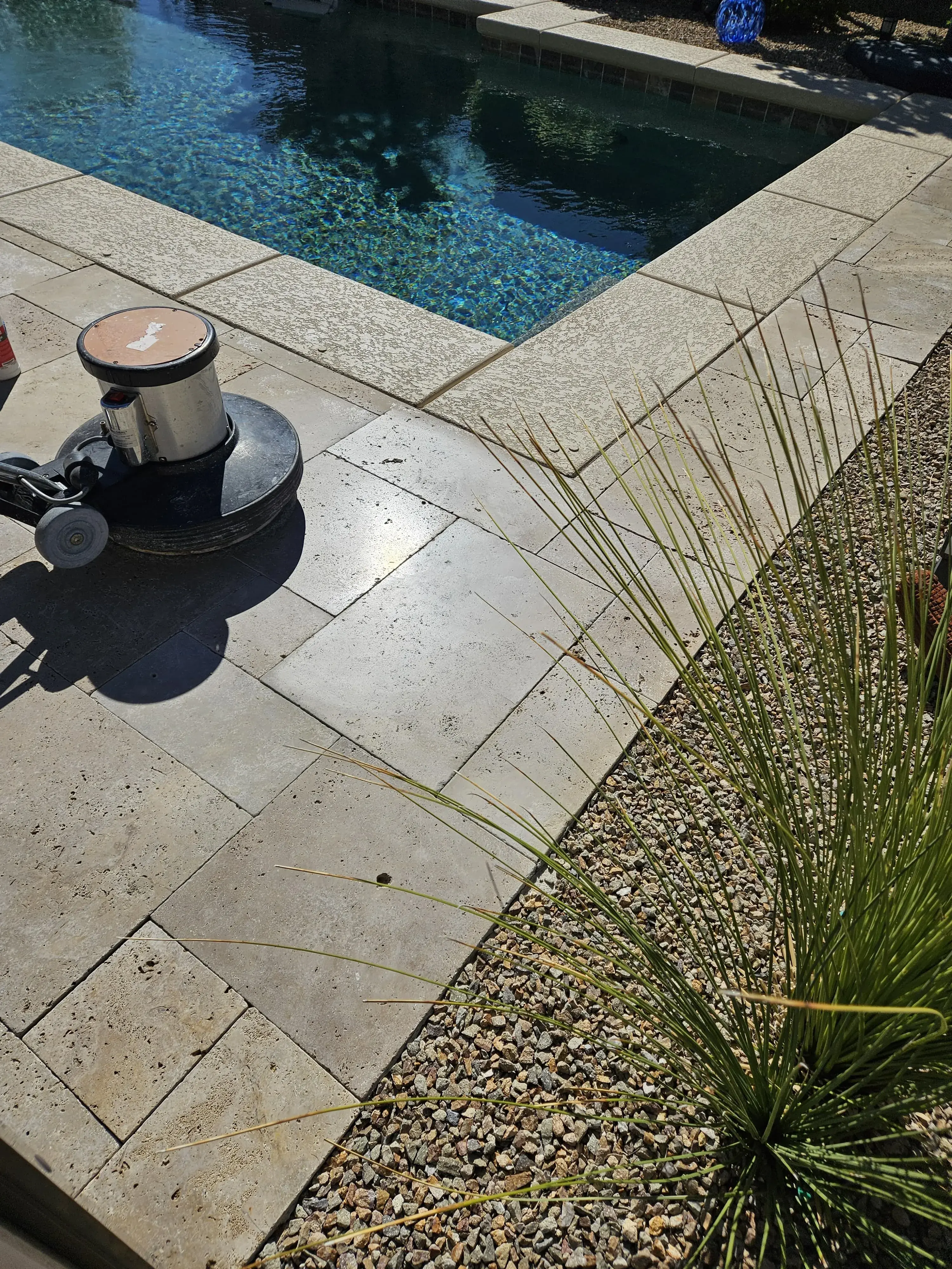 Professional machine polishing in progress along real travertine pool coping