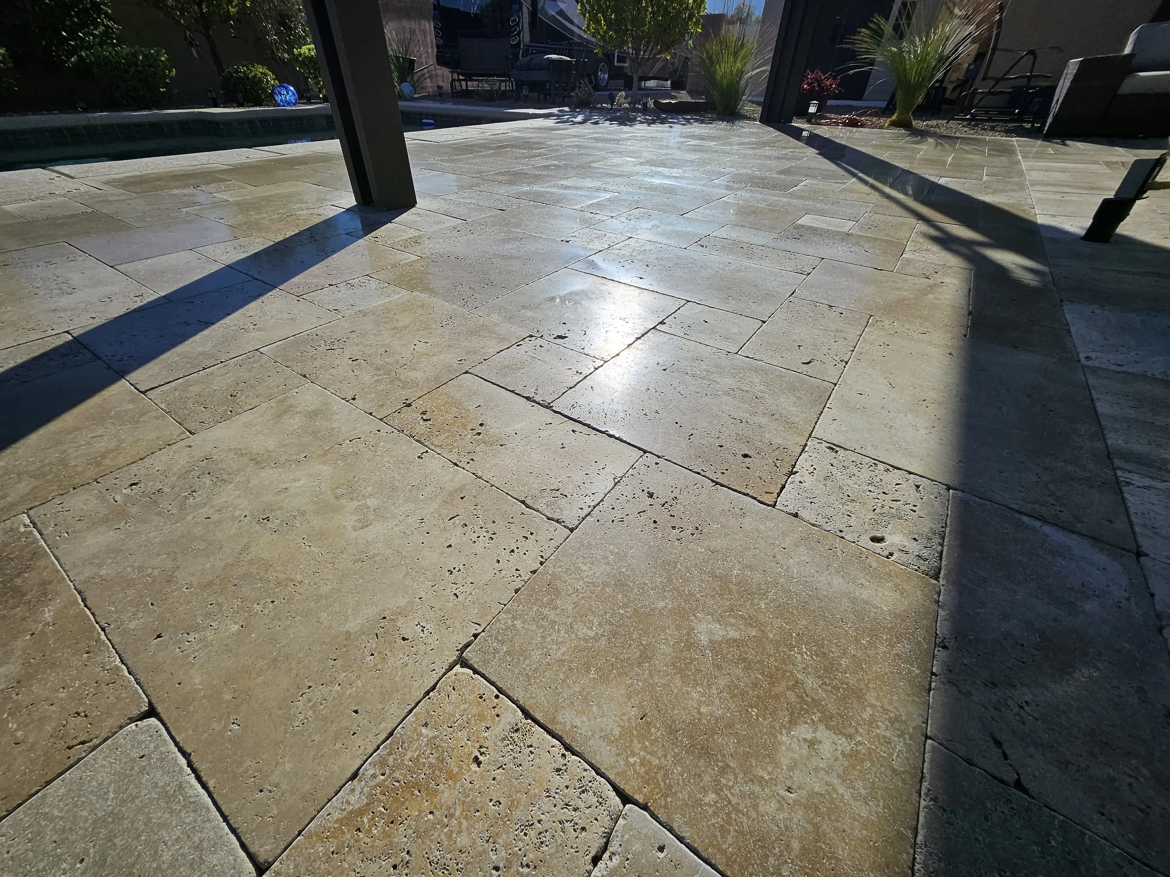 Close view of a polished travertine pool deck showing an even reflective finish